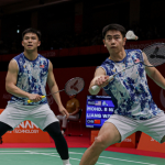 Nur Izzuddin Rumsani prepares to return the shuttlecock while Goh Sze Fei stays in ready position in their blue and white jerseys during the Asian Games.