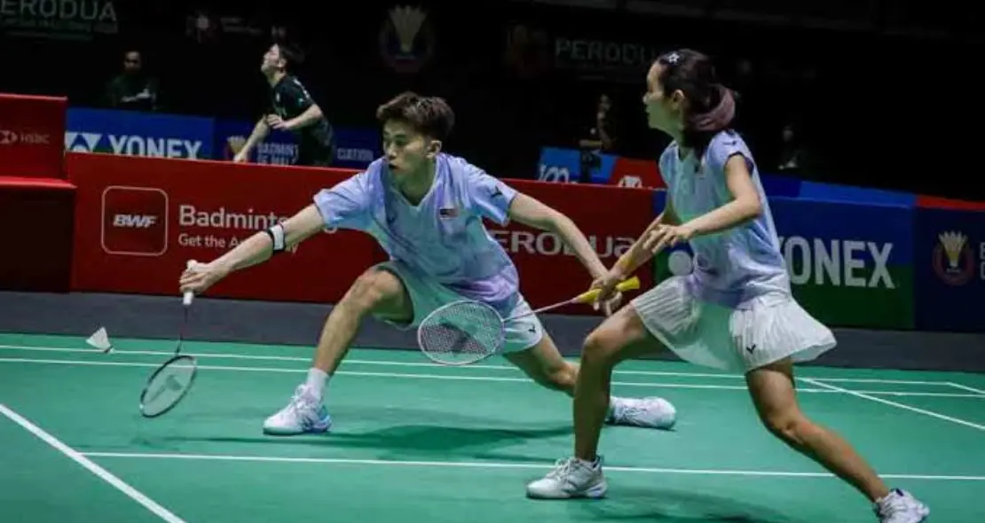 Hoo Pang Ron lunges low to play a net return while Cheng Su Yin covers the court in their lavender Malaysian jerseys.