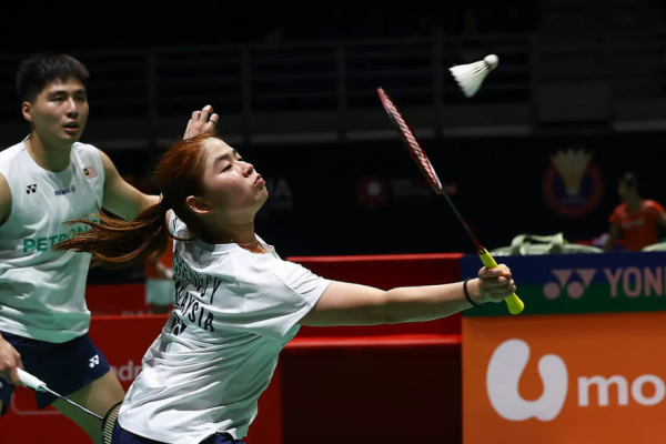 Cheng Su Yin extends her racket to play a net return while Jimmy Wong guards the rear court in their white jerseys.