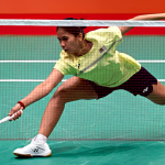 K. Letshanaa lunges deeply forward across the court to play a low net return in her yellow Malaysian national jersey.