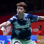 Kong Wei Xiang lunges forward low to play a backhand net shot in his blue Petronas Malaysian jersey.