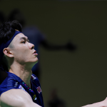 Lee Zii Jia looks up with intense focus as he strikes an overhead shot in his navy Malaysian jersey.