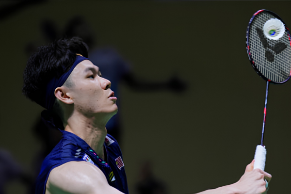 Lee Zii Jia looks up with intense focus as he strikes an overhead shot in his navy Malaysian jersey.