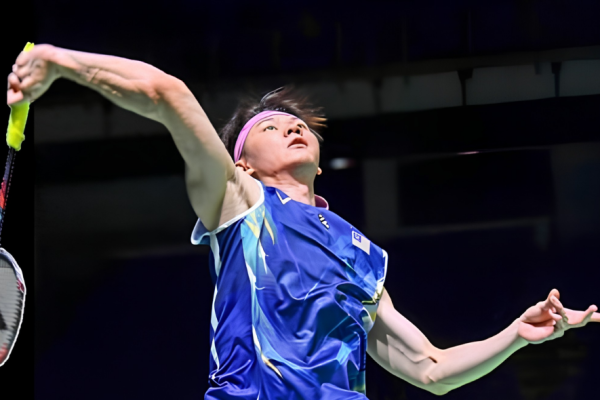 Lee Zii Jia leaps into the air to unleash a powerful overhead jump smash in his blue Malaysian jersey.