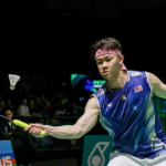 Lee Zii Jia executes a forehand return in his blue Malaysian jersey and pink headband during an international badminton match.