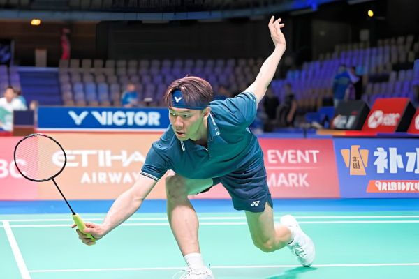 Lee Zii Jia lunges forward low to retrieve the shuttlecock at the net in his teal jersey and blue Victor headband.
