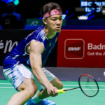 Lee Zii Jia lunges low to execute a delicate forehand return in his blue Malaysian jersey and pink headband.