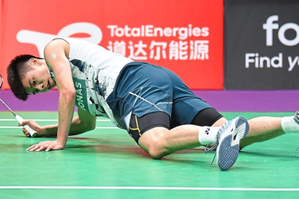 Leong Jun Hao lies exhausted on the green court floor pushing himself up in his Petronas jersey.