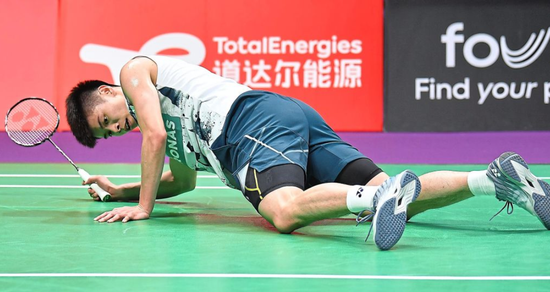 Leong Jun Hao lies exhausted on the green court floor pushing himself up in his Petronas jersey.