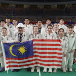 The Malaysian World Junior badminton squad and team manager Vincent Chin pose with the national flag on court in Cairo.