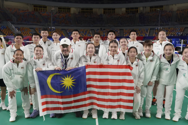 The Malaysian World Junior badminton squad and team manager Vincent Chin pose with the national flag on court in Cairo.