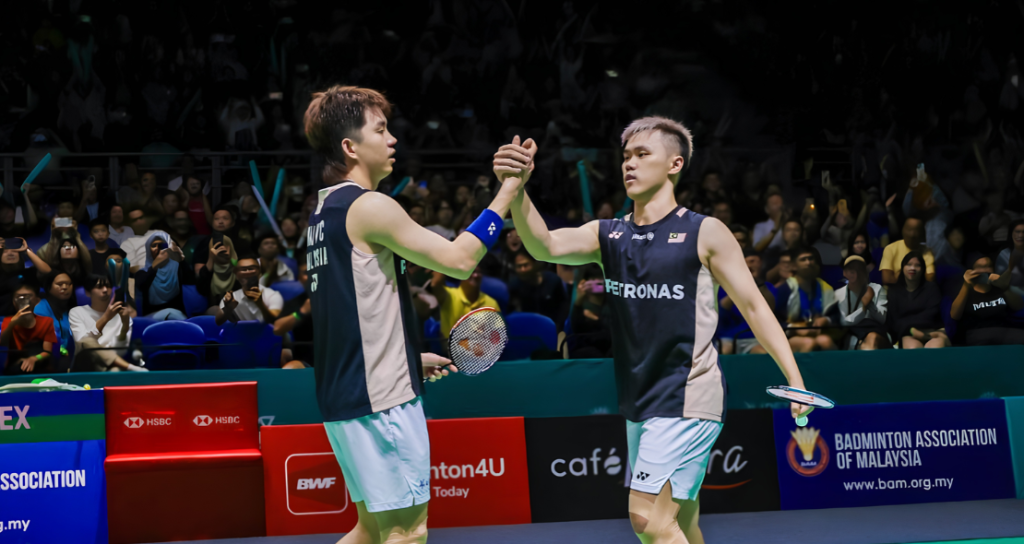 Man Wei Chong and Tee Kai Wun exchange a celebratory high five on court in their black Petronas jerseys.