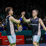 Man Wei Chong and Tee Kai Wun exchange a celebratory high five on court in their black Petronas jerseys.