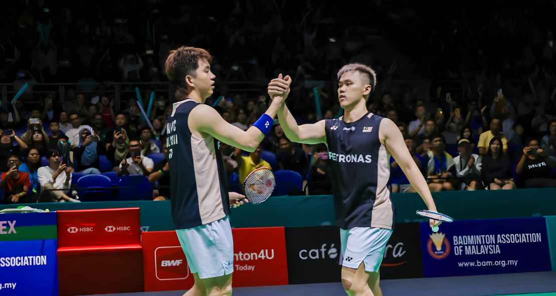 Man Wei Chong and Tee Kai Wun exchange a celebratory high five on court in their black Petronas jerseys.