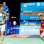 Man Wei Chong and Tee Kai Wun celebrate with passionate fist pumps after winning a thrilling match point in their white Petronas jerseys.