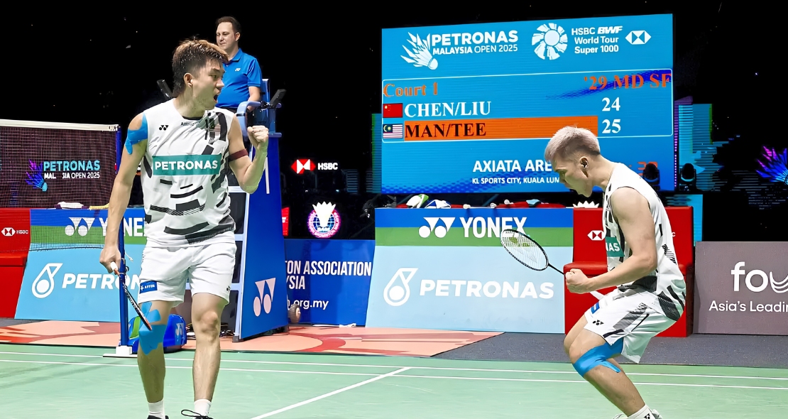 Man Wei Chong and Tee Kai Wun celebrate with passionate fist pumps after winning a thrilling match point in their white Petronas jerseys.
