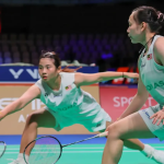 Ong Xin Yee lunges low to return a shot while Carmen Ting stays in ready position in their white Petronas jerseys.