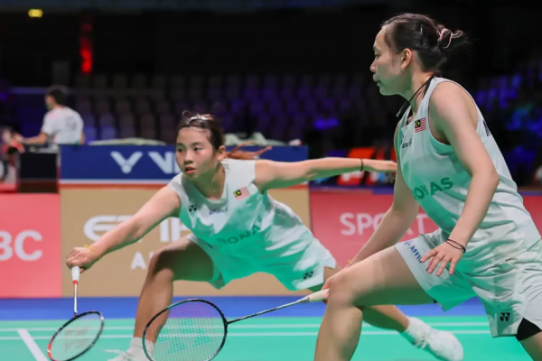 Ong Xin Yee lunges low to return a shot while Carmen Ting stays in ready position in their white Petronas jerseys.