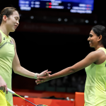 Pearly Tan and M. Thinaah smile as they hold hands in celebration wearing their lime green jerseys during the Asian Games.