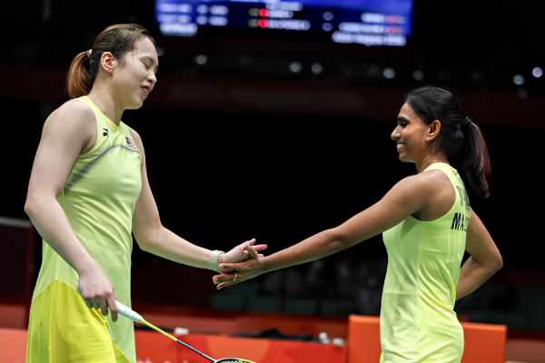 Pearly Tan and M. Thinaah smile as they hold hands in celebration wearing their lime green jerseys during the Asian Games.