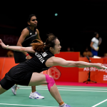 Pearly Tan lunges forward to retrieve the shuttlecock while M. Thinaah provides court coverage in their black Malaysian jerseys.