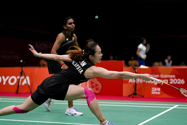 Pearly Tan lunges forward to retrieve the shuttlecock while M. Thinaah provides court coverage in their black Malaysian jerseys.