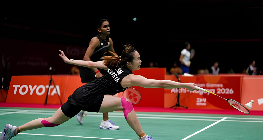 Pearly Tan lunges forward to retrieve the shuttlecock while M. Thinaah provides court coverage in their black Malaysian jerseys.