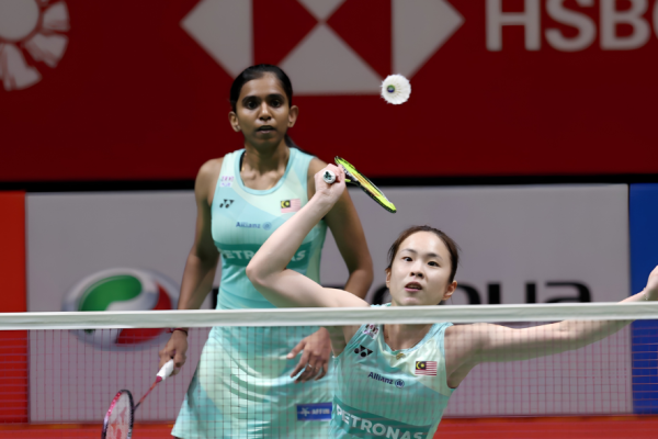 Pearly Tan prepares to intercept the shuttlecock at the net while M. Thinaah covers the back court in their turquoise Malaysian jerseys.