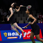 Pearly Tan leaps high in mid-air to smash while M. Thinaah guards the front court in their black Malaysian jerseys.