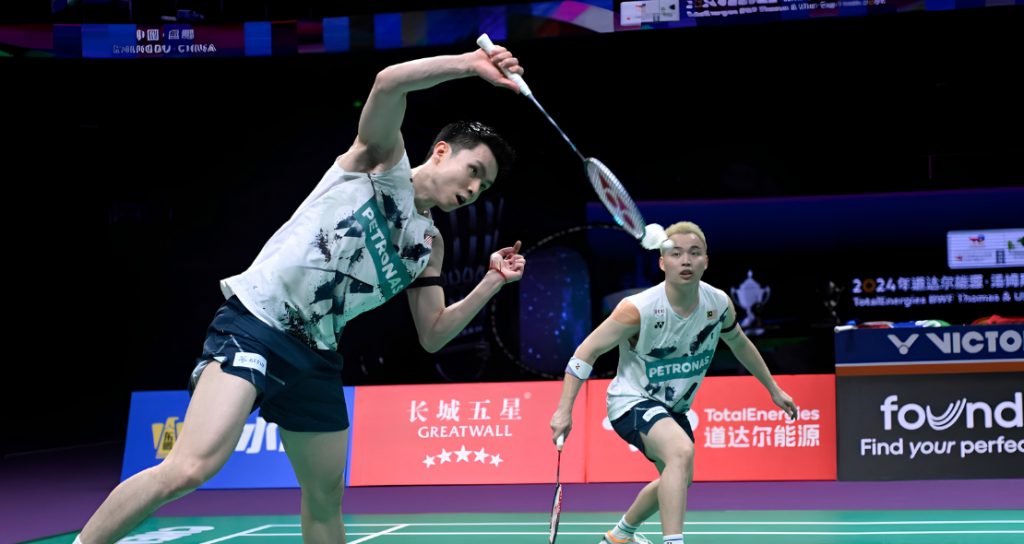 Soh Wooi Yik executes an overhead return while partner Aaron Chia covers the court in their white Petronas jerseys.