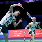 Soh Wooi Yik executes an overhead return while partner Aaron Chia covers the court in their white Petronas jerseys.